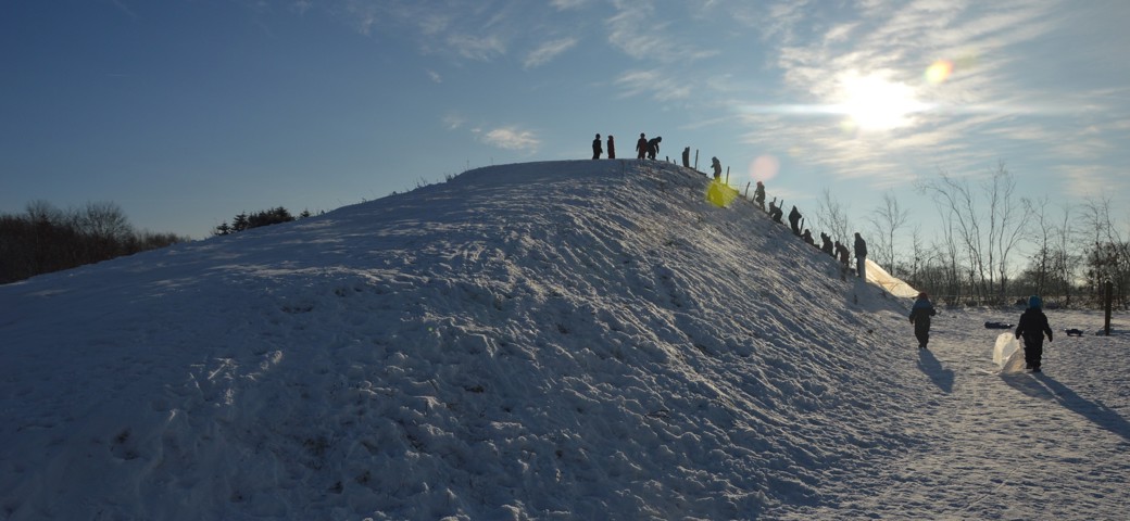 Børn står oppe på toppen af en snedækket bakke